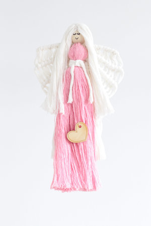 Macrame hand woven with cord guardian angel with wings and pink dress on white background