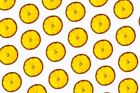 Pattern made of backlit orange slices on white background
