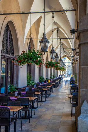 Arcade of Cloth Hall at Market Square in Cracow with restaurant tablesの写真素材