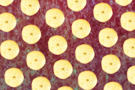 Pattern made of slices of Jonagold apples on closeup on jonagold apple peel in backgroundの写真素材