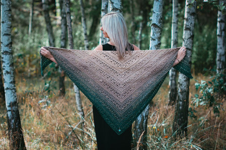 Fourty years old woman show hand crochet made by herself ombre shawl in birch groveの写真素材