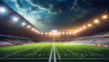 A football stadium illuminated by bright lights, with green turf and clear markings, under a dramatic cloudy night sky, creating an electrifying ambiance, blured backgroundの写真素材