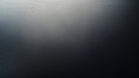 Dark water with subtle ripples reflecting sunlight, creating a gradient from light to dark. Ai generated imageの素材