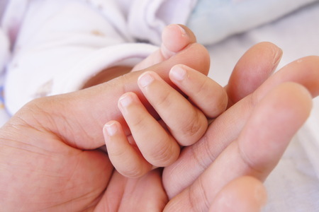 Baby sleeping and holding hand with father handの写真素材