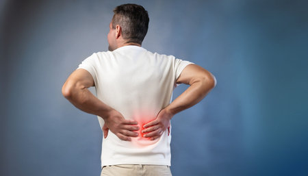 Man suffering from back pain on blue background. Backache concept.の素材