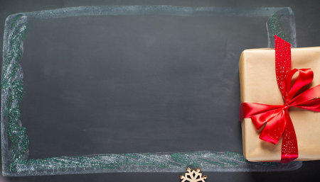 Gift box with red ribbon and christmas decoration on blackboardの素材