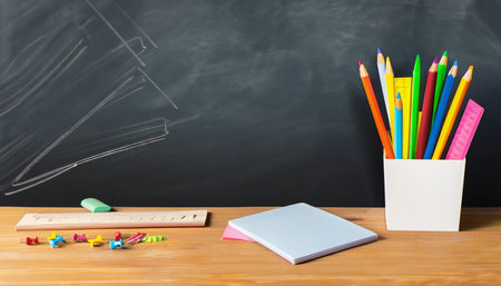 Back to school concept. School supplies on wooden desk with blackboard backgroundの素材