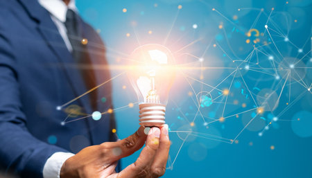 Close up of businessman holding lightbulb with connection lines and dotsの素材