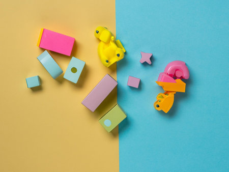 Colorful plastic toy blocks on yellow and blue background. Top viewの素材