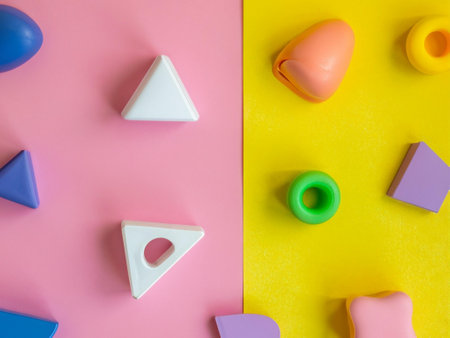 Colorful plastic geometric shapes on pink and yellow background. Top view.の素材
