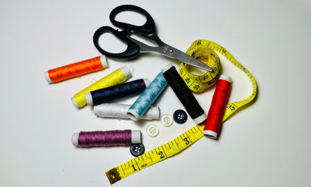 spools of thread, scissors, buttons and measuring tape on white backgroundの写真素材