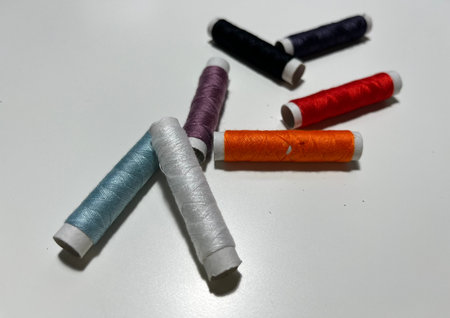 Sewing threads of different colors on a white background close up