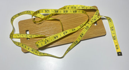 Wooden cutting board with a tape measure on a white background.の写真素材