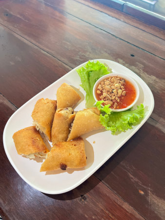 Fried spring rolls with spicy sauce on wooden table, Thailand.の写真素材