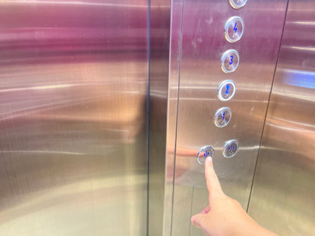 Close-up of hand pressing elevator button.の写真素材