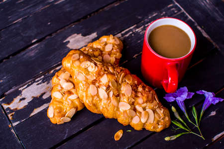 Breakfast with fresh almond twist breads and coffee on black wooden table.の写真素材