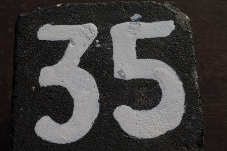 number 35 (thirty-five) white painted on black stone