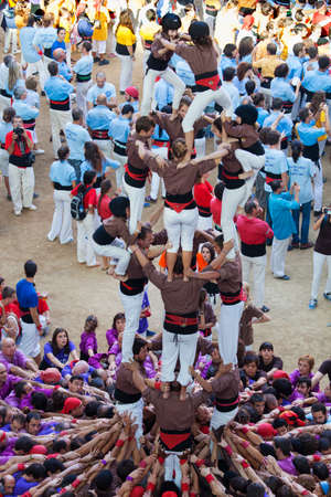 TARRAGONA, SPAIN - OCTOBER 6: Collas different members involved to form a castle with \"Reus Xiquets\", contest castells of Tarragona celebrations in Tarraco Arena Plaça,  October 6, 2012, Tarragona, Spainのeditorial素材