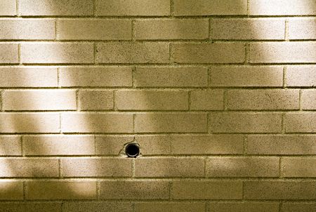 A drilled hole in a shadowed brick wall. の写真素材