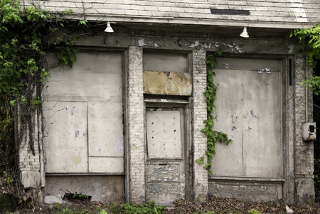 A very old building, still standing, peeling, boarded up and vine covered. の写真素材