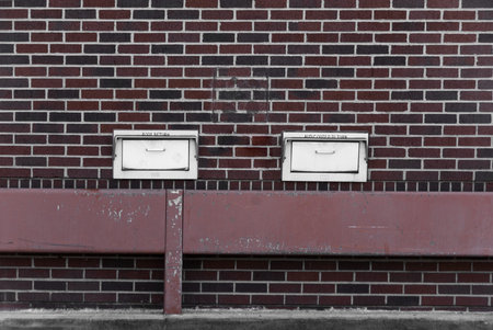 Library dorp boxes on a red brickwall with railing. の写真素材