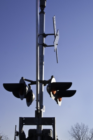 A railroad crossing signal on post with lights and signs. の写真素材