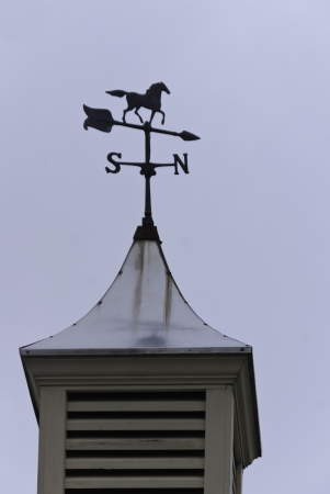 A weatehr vane on a cupula agaginst an light overcasat sky. の写真素材