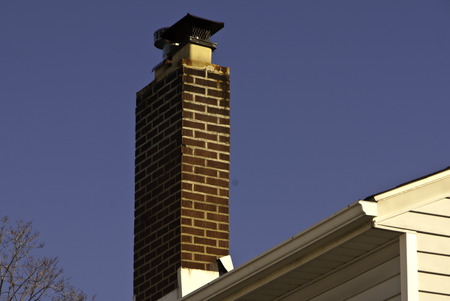 A red brick chimney against a bright blue sky.の写真素材