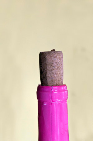 A cork in a bottle with pink wrapping all on a yellow background.の写真素材