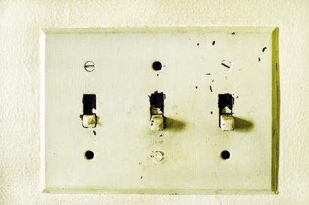An aged and yellowed light switch panel.の写真素材