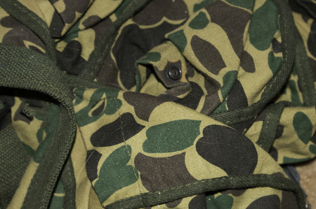 A duffle bag in camaflauge colors with straps and buttons.の写真素材