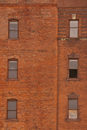 An old red brick building with six windows one open.