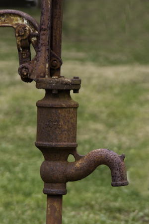An old and well used rusted hand water pump.の写真素材