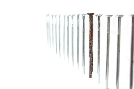 Row of the new nails with one old and rusty between them. Weak point metaphorの写真素材