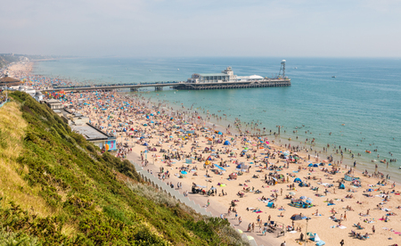 Bournemouth, UK - August 28, 2017: Busy beach in a hot summer day with Pier Amusements in the background. View from the top of the cliffsのeditorial素材