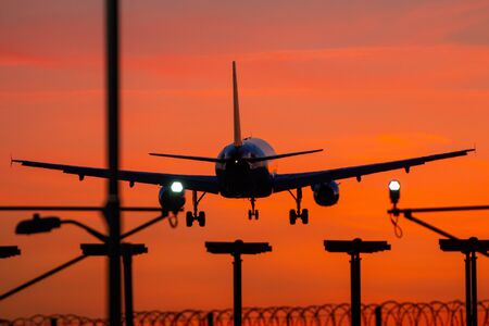 Passenger plane landing during orange sunsetの写真素材