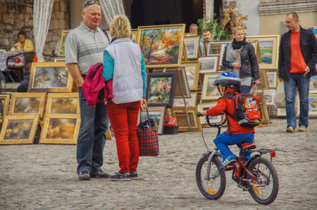 Kazimierdz Dolny, lubelskie / Poland-10-13-2013 traditional weekend trade in paintings on the market in the tourist town of Kazimierz Dolny, picnic atmosphere, walking tourists, child on a bikeのeditorial素材