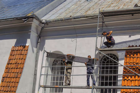 WilkÃ³w, lubelskie / Poland 06-30-2012, On a sunny day, a group of workers on scaffolding renovates the church in WilkÃ³w, Roof reparing, safe work at heights and the risk of an accidentのeditorial素材