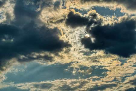 the sun behind the clouds, the dramatic sky during the changing weather, the sun's rays piercing the cloudsの写真素材