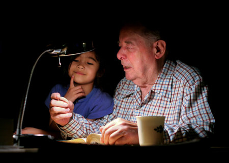 Elderly grandpa talking to great grand daughter about silver coin in hand