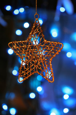 Gold star ornament with Christmas lights in background.の写真素材