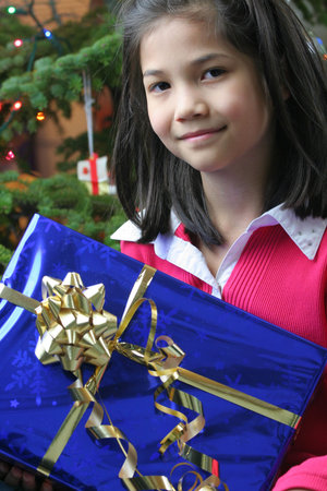 Happy little eight year old girl holding her Christmas presents 