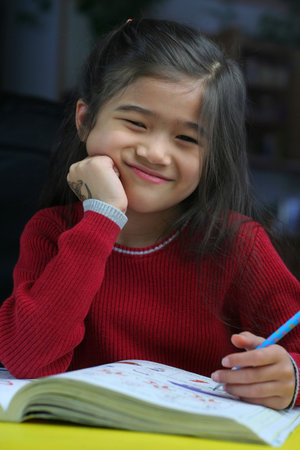 Six year old girl doing her homework at night. 