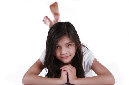 Beautiful ten year old girl happily relaxing on floorの写真素材