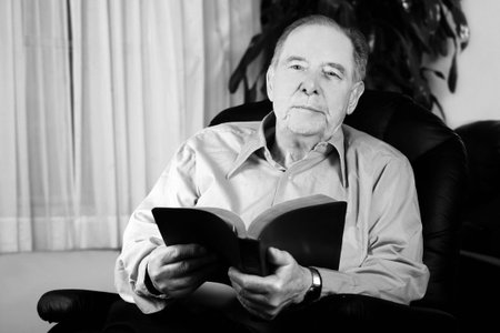 Elderly man reading Bible in reclinerの写真素材
