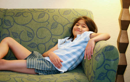 Little girl relaxing on green couch or sofaの写真素材