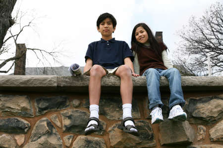Two children sitting on rock ledge outdoors,  brother and sisterの写真素材