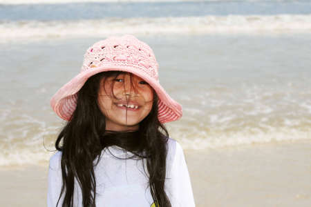 Cute little girl in pink hat at beachの写真素材