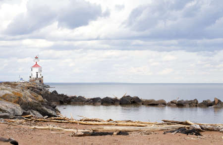 Lighthouse at end of rocky pier along Lake Superiorの写真素材