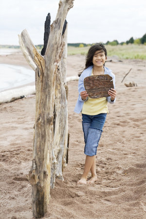 Little girl on beach holding up blank wooden signの写真素材